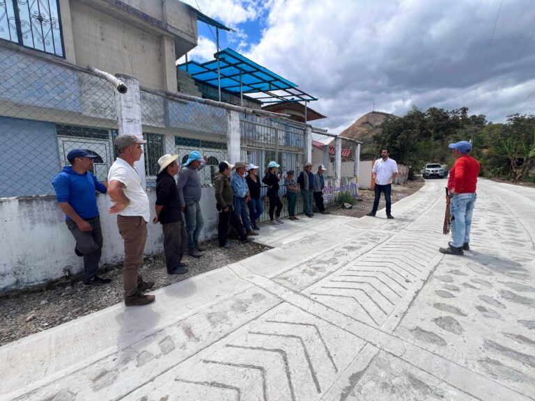 Funcionario dialogando con un grupo de habitantes rurales al borde de un tramo recién construido de placa huella en el departamento de Nariño.