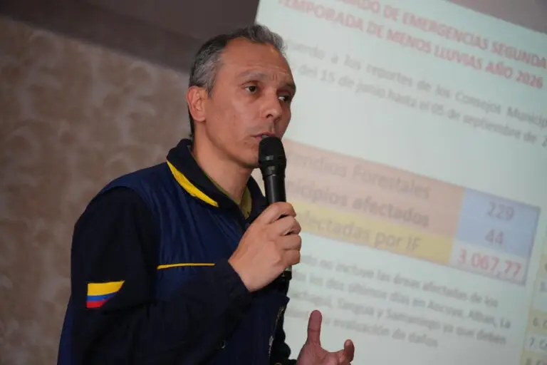 Funcionario hablando por un micrófono durante una presentación; al fondo, una diapositiva proyecta estadísticas sobre incendios forestales y municipios afectados.