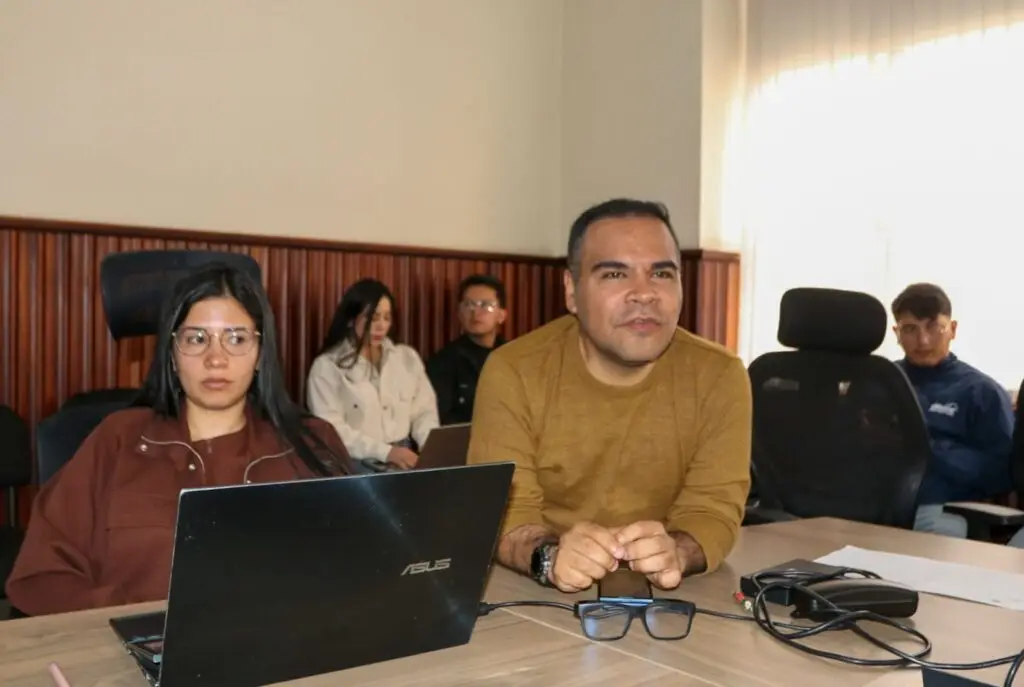 Un hombre y una mujer sentados en una mesa de trabajo observan atentamente una presentación, apoyados con un computador portátil, durante la jornada de revisión técnica de proyectos en Nariño.