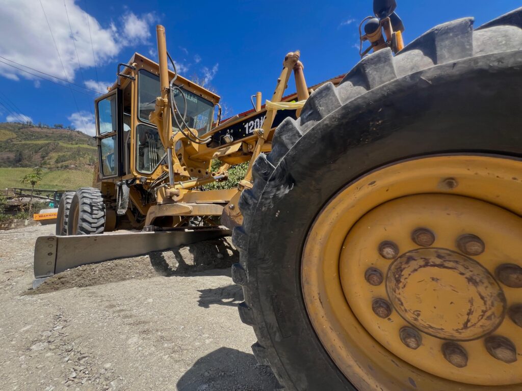 Motoniveladora de maquinaria amarilla realizando trabajos de nivelación sobre una vía terciaria no pavimentada en el occidente de Nariño.