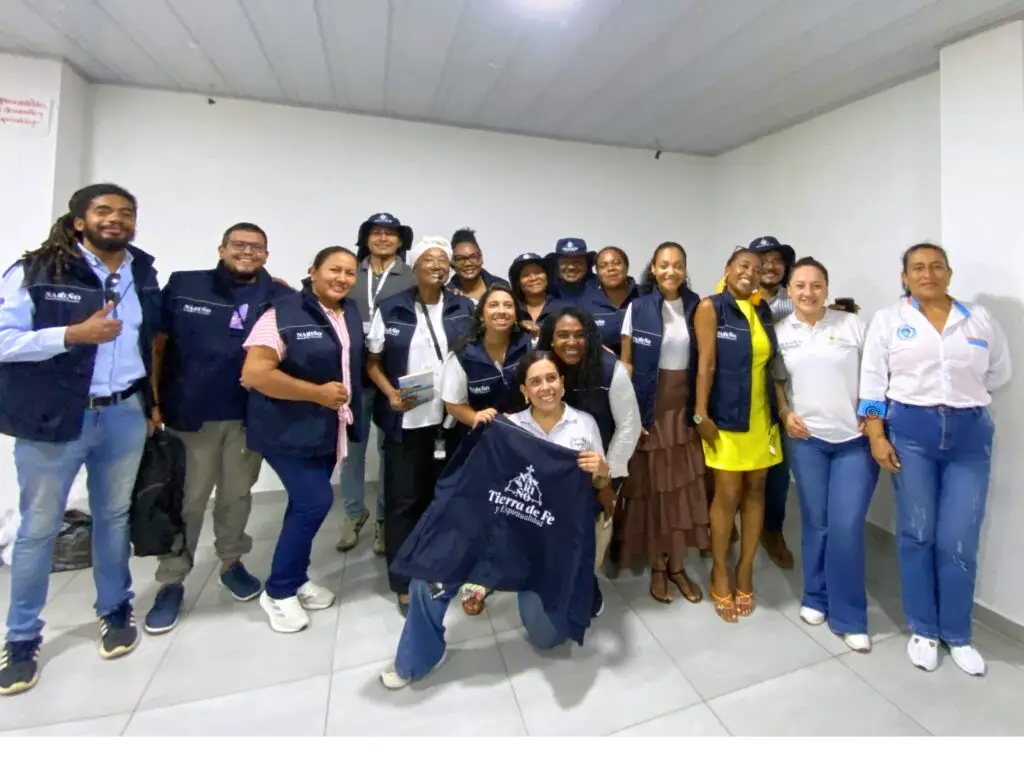 Grupo de guías profesionales de turismo y representantes institucionales de Tumaco posan con chalecos y elementos de trabajo entregados durante una jornada de fortalecimiento turístico.