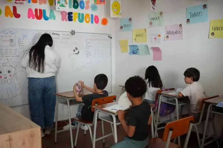 Niñas y niños participan en una actividad pedagógica dentro de un aula, acompañados por una orientadora que desarrolla ejercicios sobre emociones y convivencia.