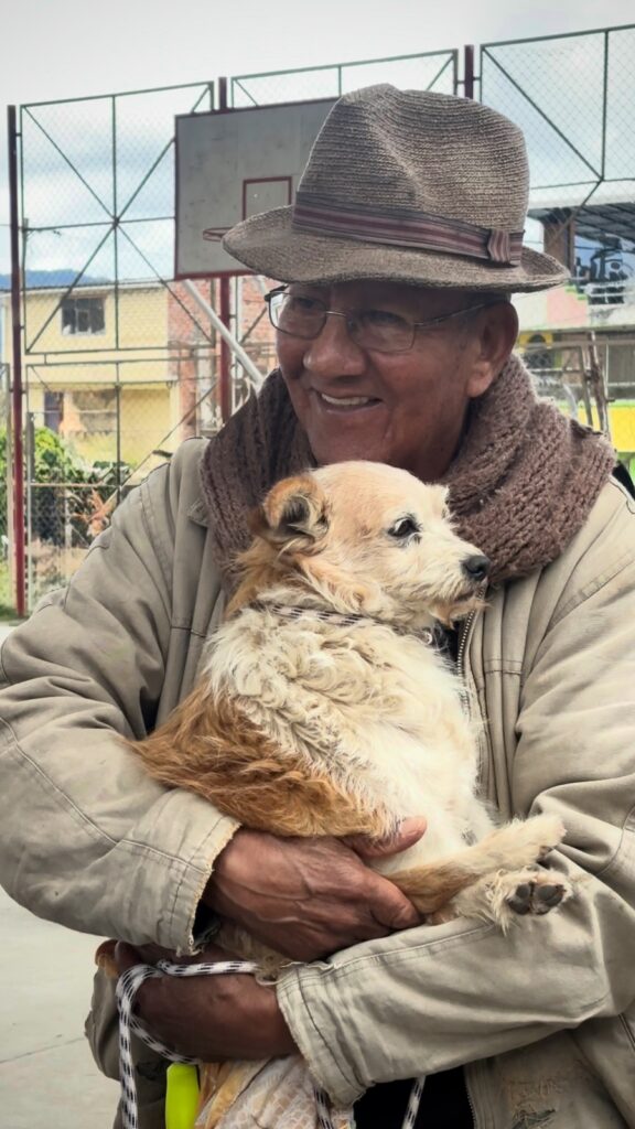 Adulto mayor sostiene a su perro durante una jornada comunitaria de protección y bienestar animal.
