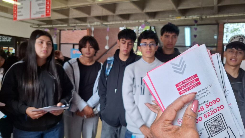 Jóvenes reciben material informativo sobre prevención, denuncia y rutas de atención frente a la trata de personas.