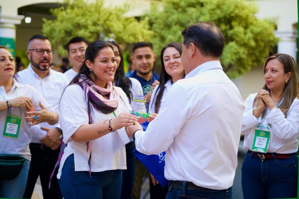 Funcionaria recibe un reconocimiento al estand ganador durante la Feria de Relacionamiento Estado Ciudadano de la Gobernación de Nariño.