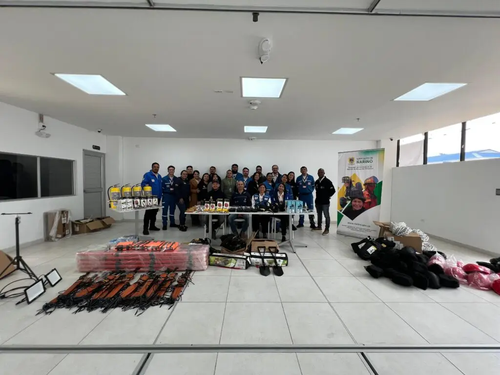 Muestra de los cuatro kits de rescate vertical y equipos de emergencia distribuidos sobre el piso y mesas en un salón, con voluntarios de la Cruz Roja y funcionarios posando al fondo.