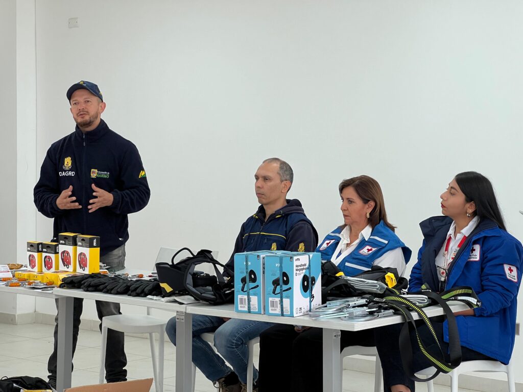 Un funcionario del DAGRD intervención en la mesa principal de la entrega de equipos, rodeado por representantes de la Cruz Roja Seccional Nariño y cajas con elementos de rescate.