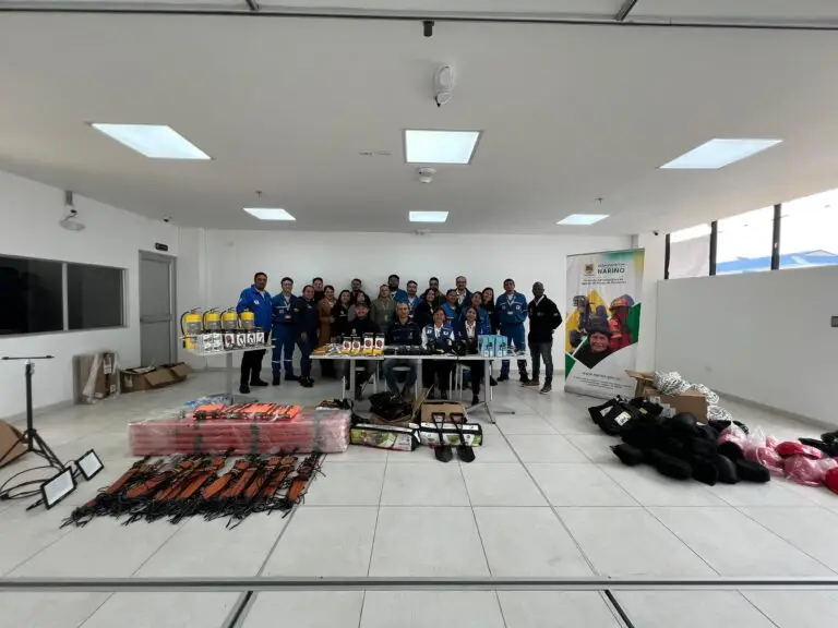 Muestra de los cuatro kits de rescate vertical y equipos de emergencia distribuidos sobre el piso y mesas en un salón, con voluntarios de la Cruz Roja y funcionarios posando al fondo.