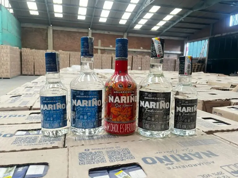 Cinco botellas con variadas presentaciones y ediciones especiales de Aguardiente Nariño alineadas sobre cajas en un centro de acopio.