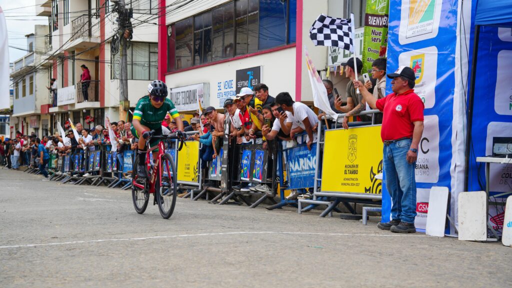 Ciclista cruza la línea de meta durante una de las etapas de la Décima Vuelta a Nariño, mientras el público acompaña la competencia.