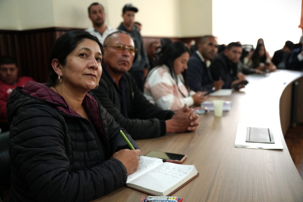 Representantes de las comunidades de Samaniego escuchan y toman apuntes durante una mesa de diálogo sobre infraestructura vial y necesidades territoriales.