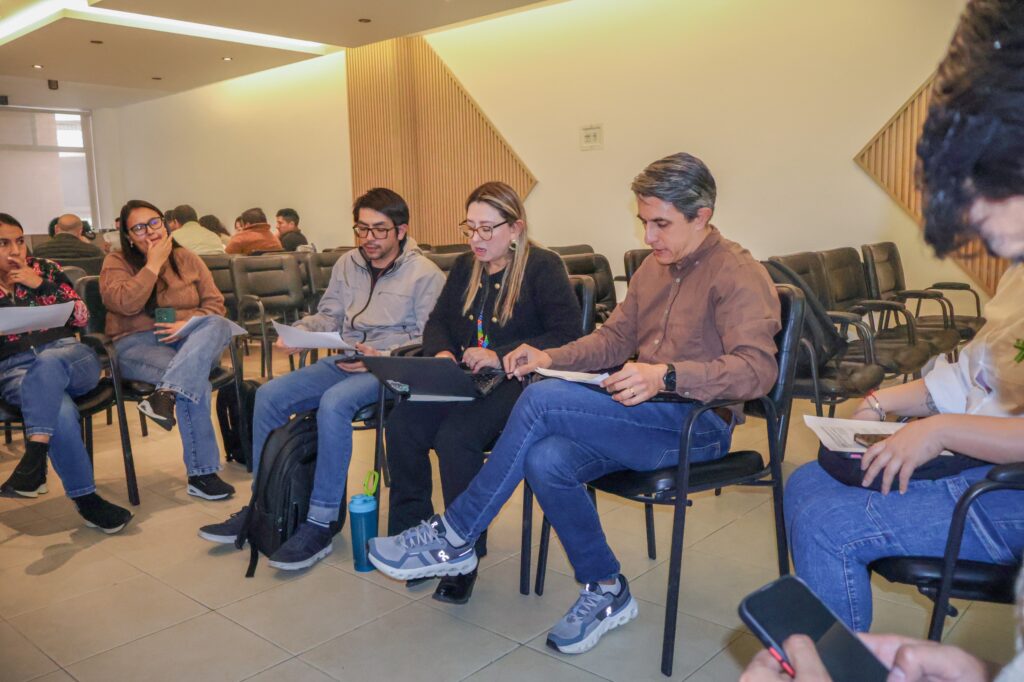 Asistentes al taller de la Mesa de Ciencia, Tecnología e Innovación Agropecuaria sentados en mesa de trabajo revisando documentos con un computador portátil.   