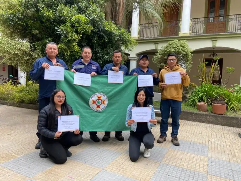Participantes del Curso de Coordinador Logístico de Salvamento Minero posan con sus certificados y una bandera del Servicio Nacional de Salvamento Minero.