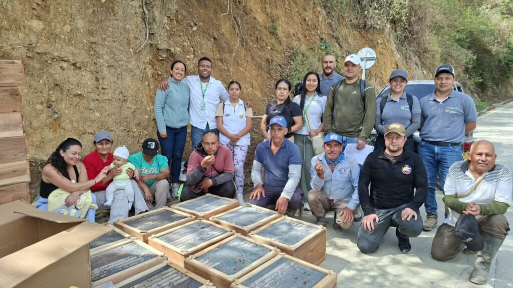 Campesinos y técnicos de la Gobernación de Nariño posando junto a cajas de colmenas entregadas al borde de una carretera rural en Leiva.