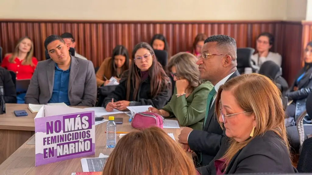 Participantes de una sesión institucional sobre prevención de feminicidios en Nariño, con un cartel que dice “No más feminicidios en Nariño”.