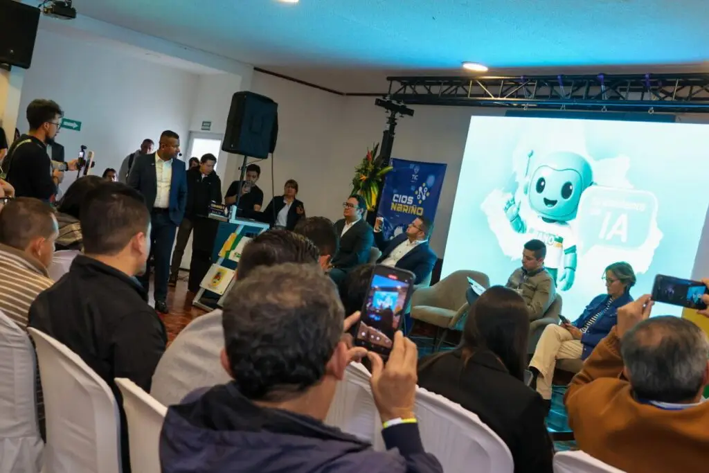 Asistentes participan en una presentación sobre inteligencia artificial durante una jornada tecnológica, mientras en una pantalla se proyecta la imagen del asistente virtual Ñaño.