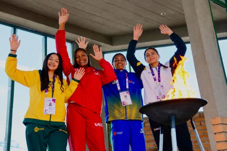 Cuatro jóvenes deportistas de las delegaciones de Cauca, Valle del Cauca, Chocó y Nariño levantan sus manos junto al fuego deportivo durante la inauguración de los Juegos Intercolegiados.