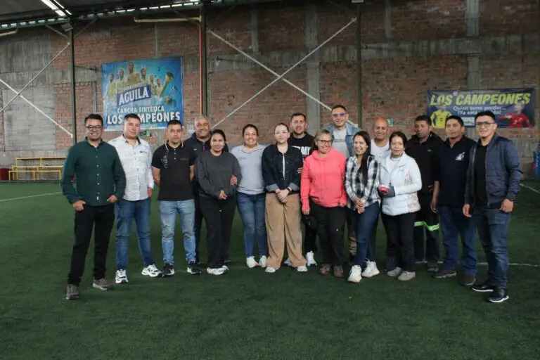 Fotografía grupal de los asistentes a la capacitación de salvamento minero posando sonrientes en una cancha sintética techada.