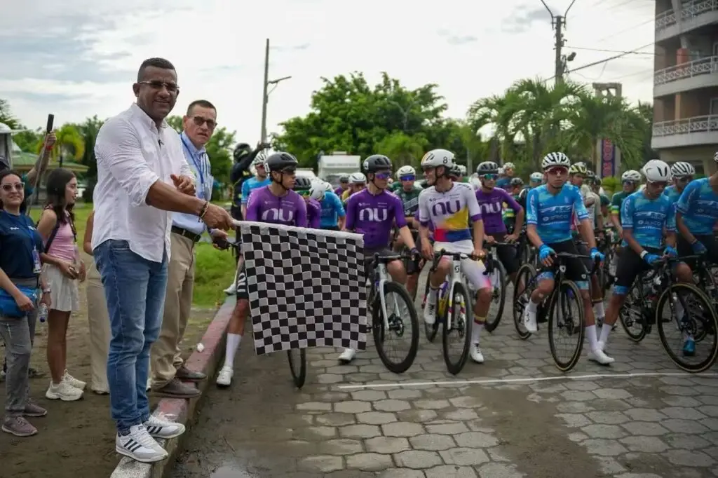 El Gobernador Luis Alfonso Escobar ondeando la bandera a cuadros en la línea de partida junto a los ciclistas del equipo NU Colombia encabezando el pelotón en Tumaco.